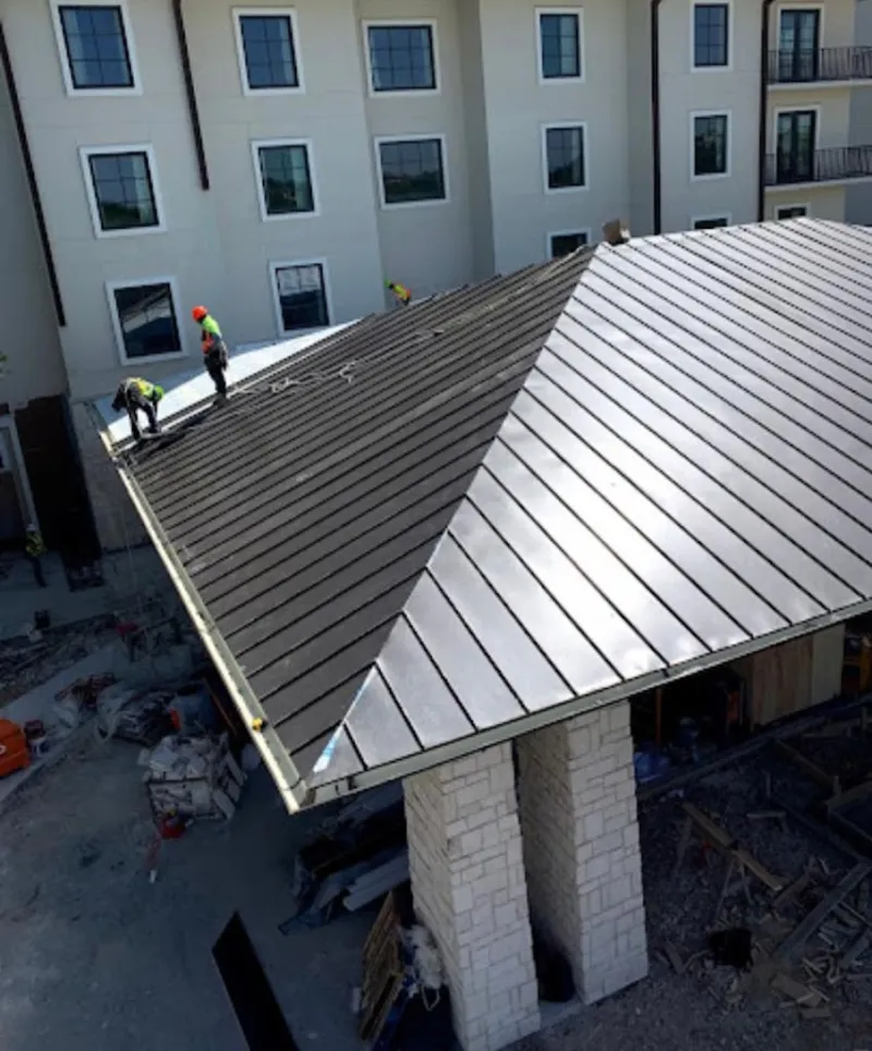 Crew installing standing seam metal roof panels on a commercial project in Woodfin